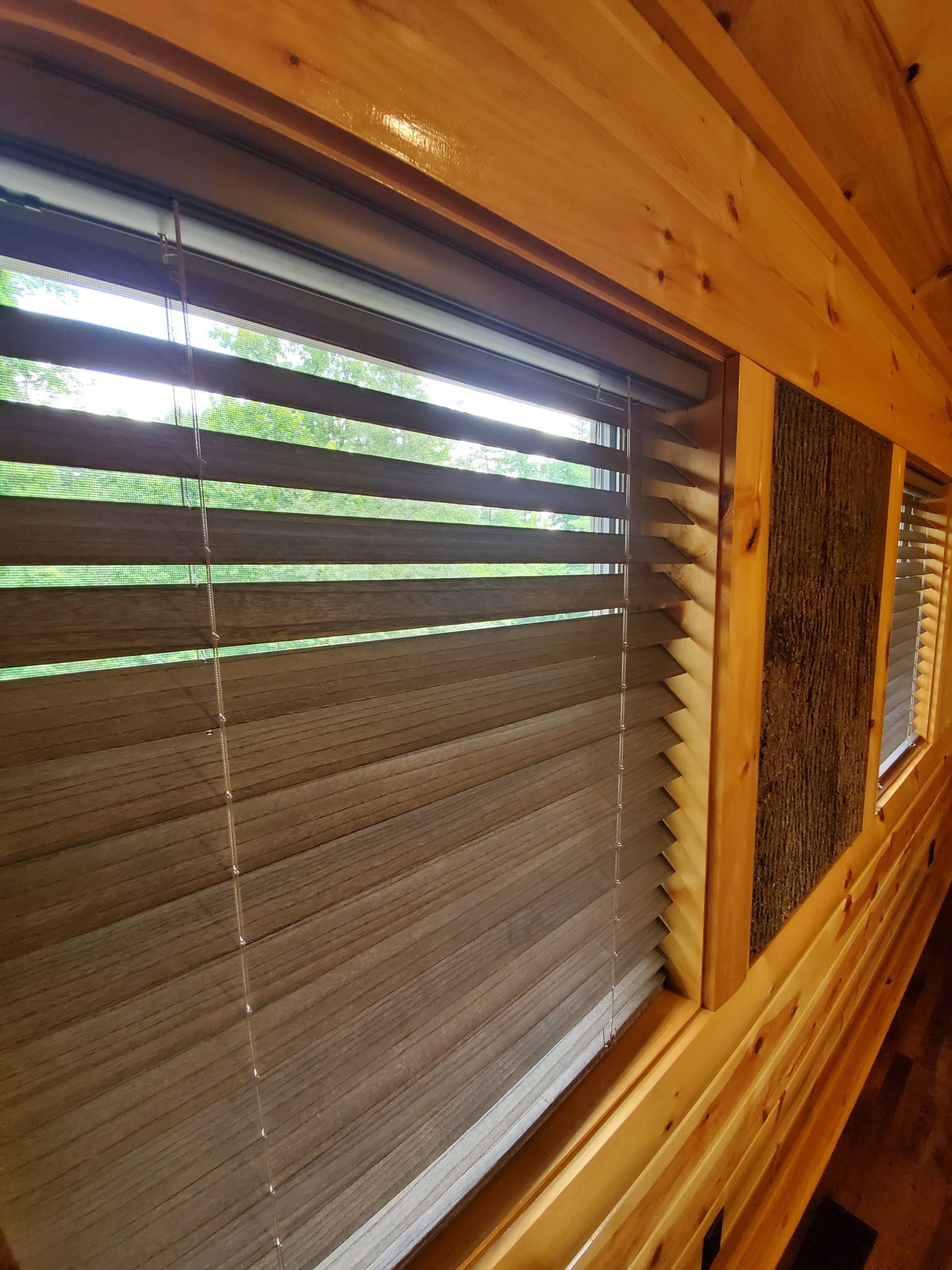 Wooden cabin interior with closed blinds, natural light, and textured wood.