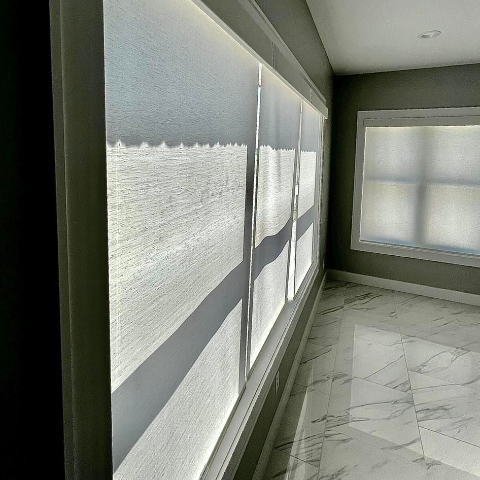Interior room with light filtering blinds on large windows; sunlight, reflective floor.