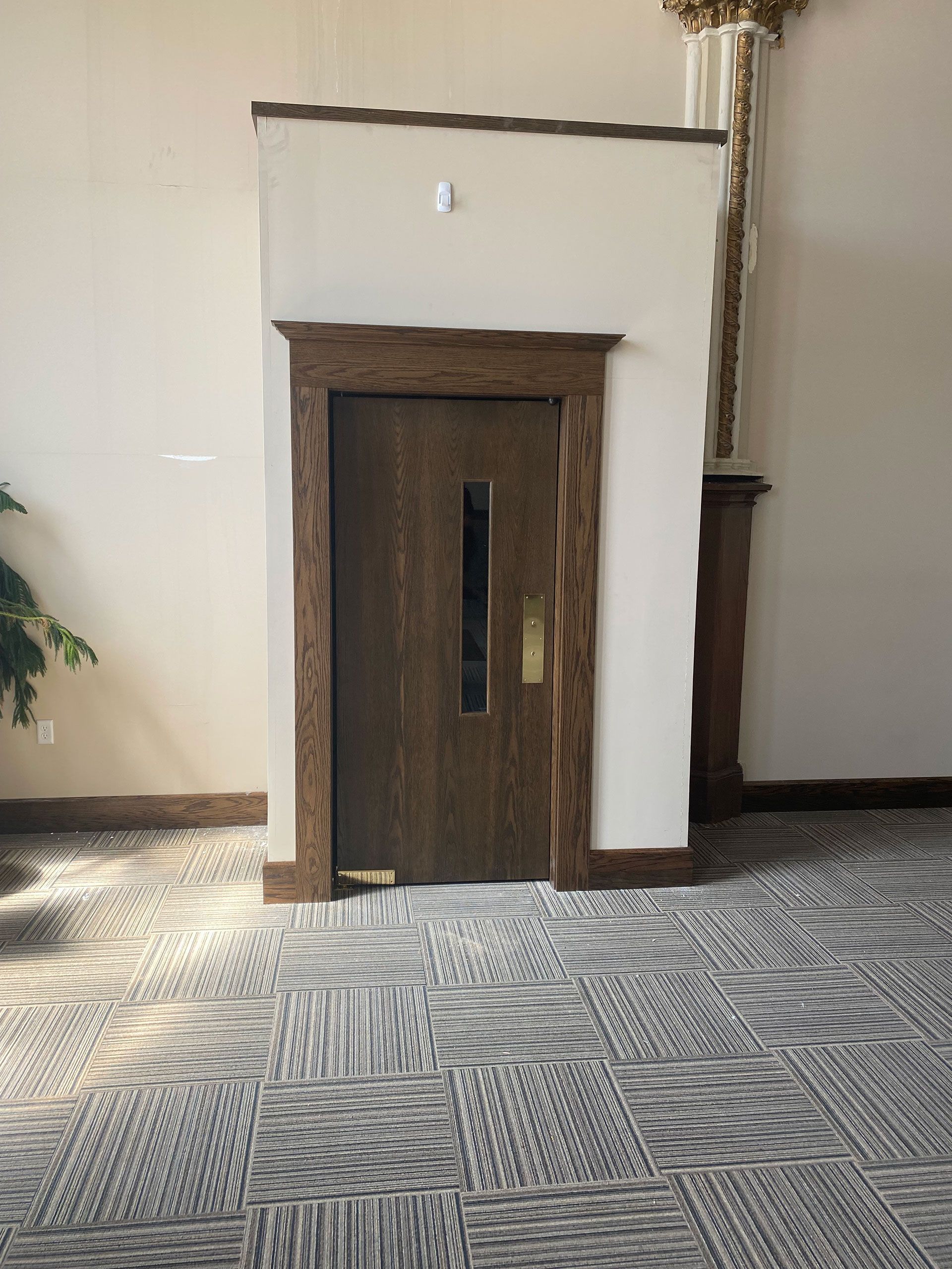 A room with a wooden door and a carpeted floor.