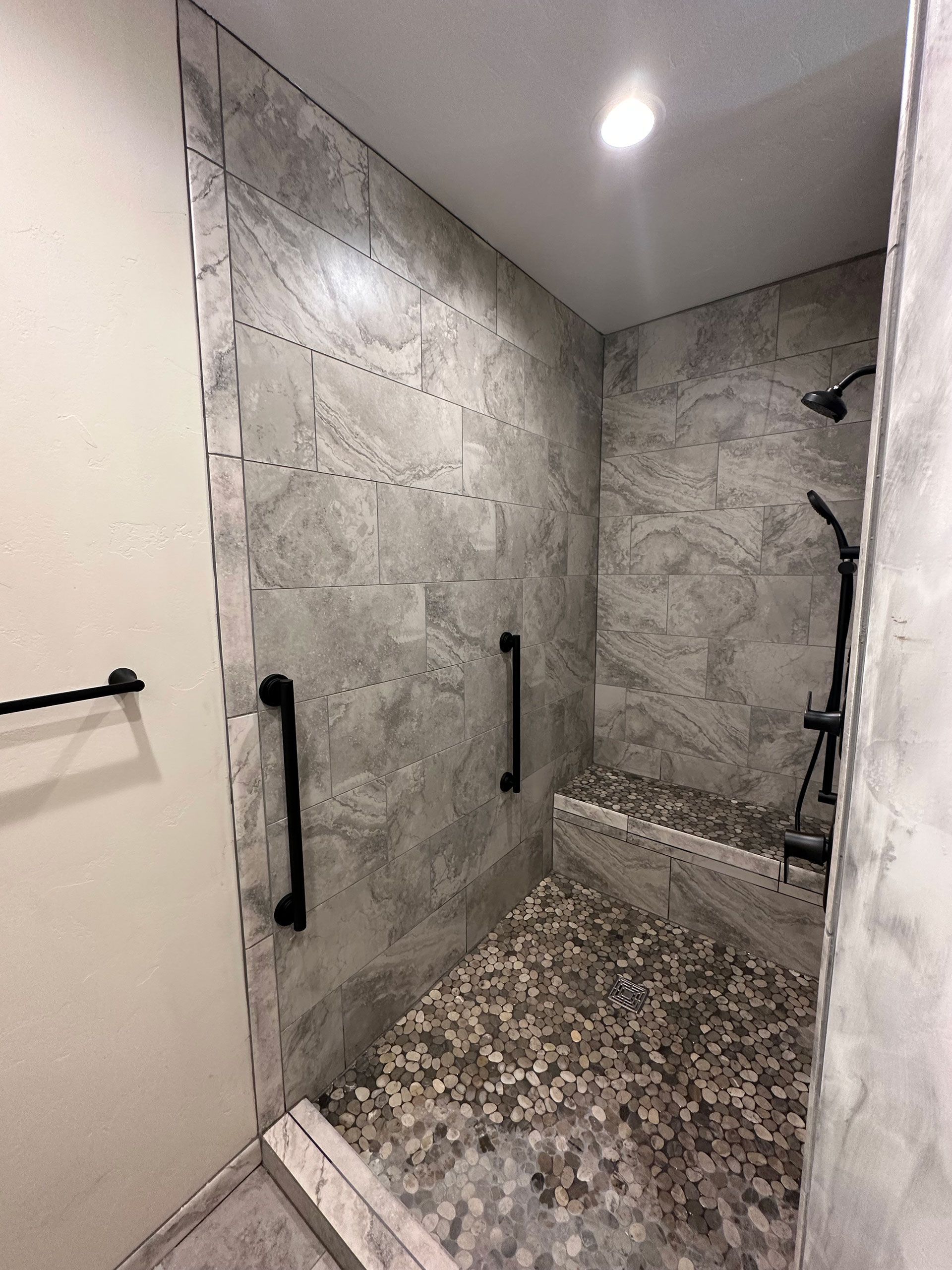 A bathroom with a walk in shower and a bench.