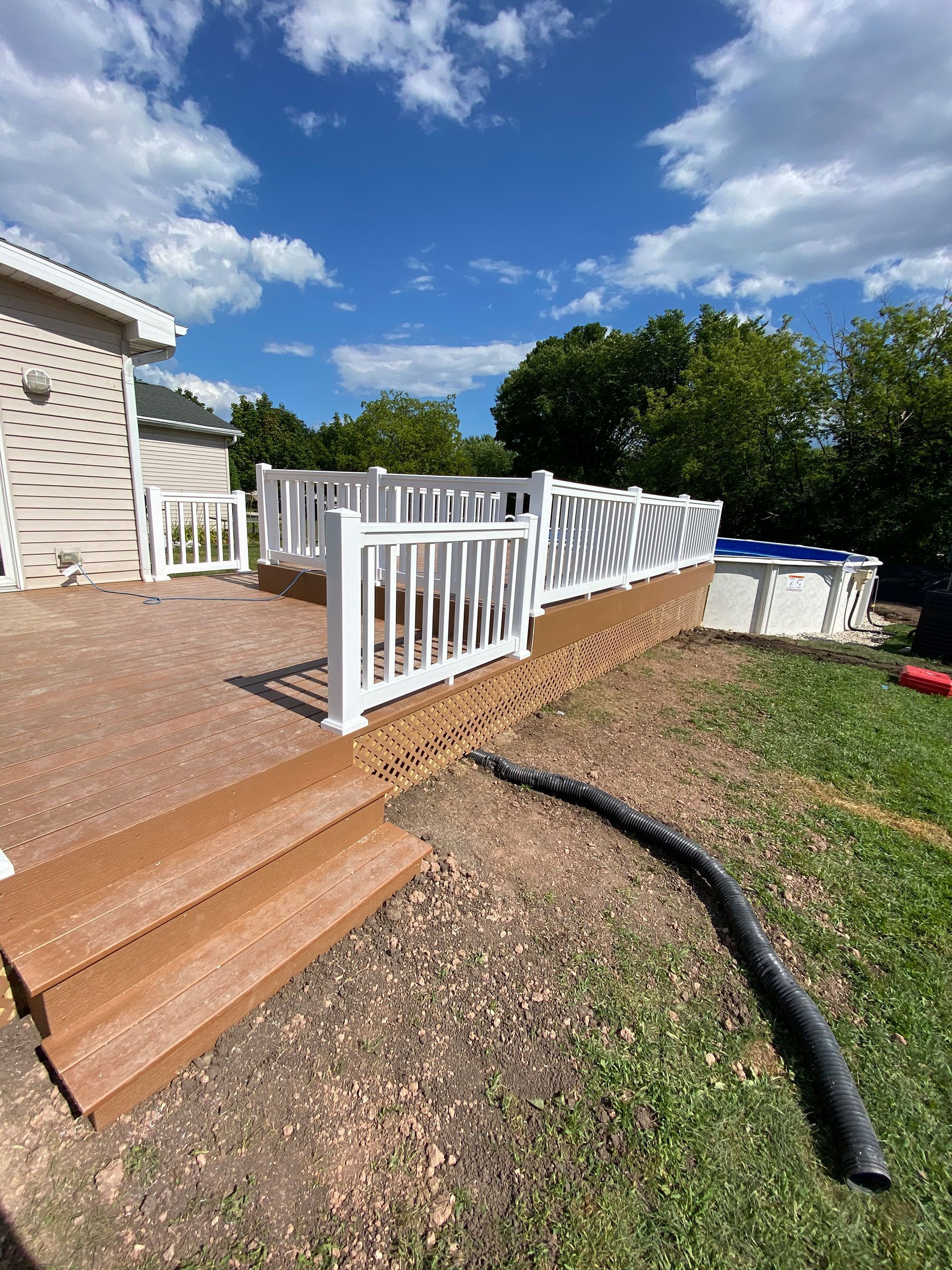 A deck with a white railing is being built next to a pool.