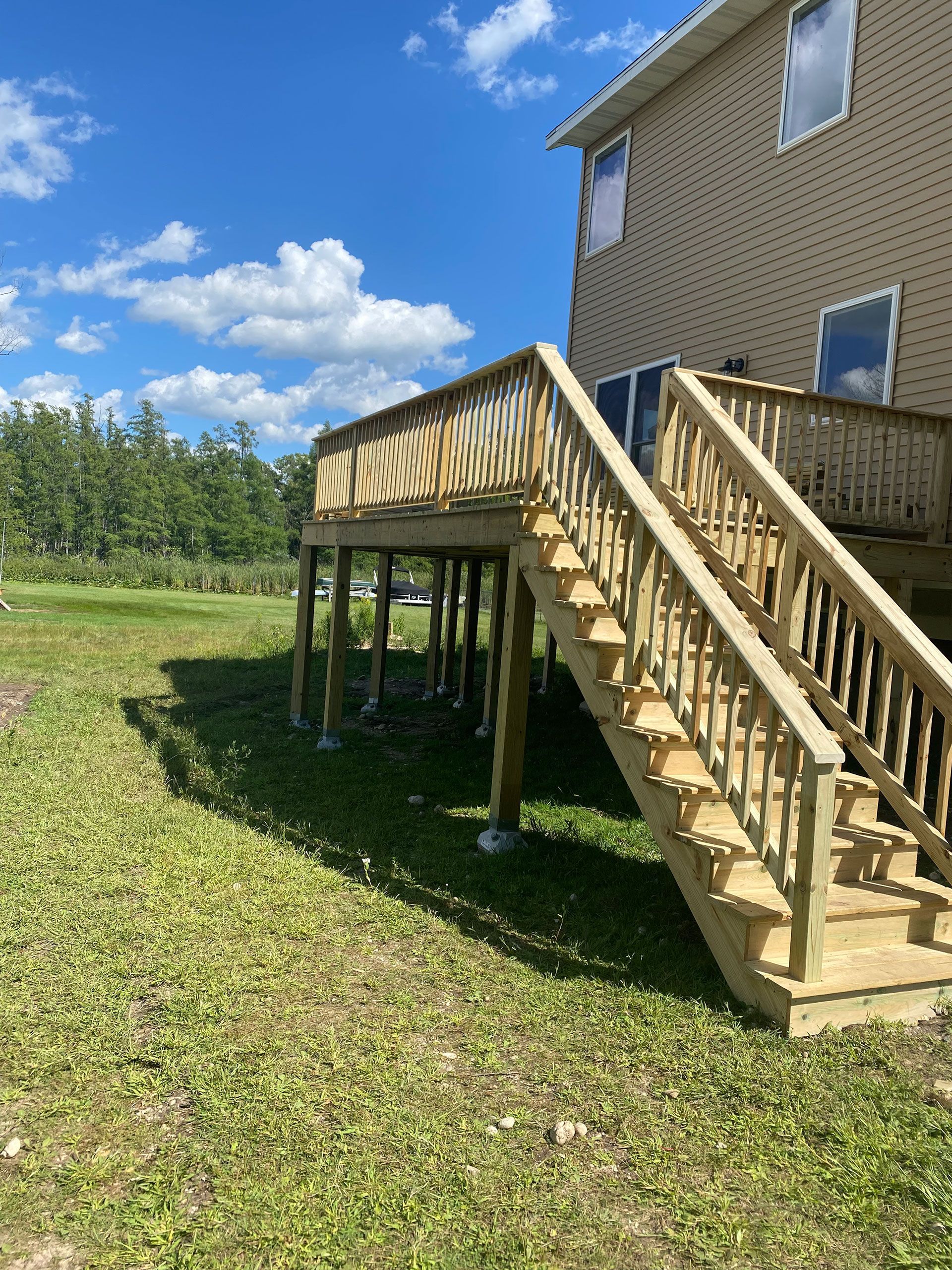 A wooden deck with stairs leading up to it in front of a house.