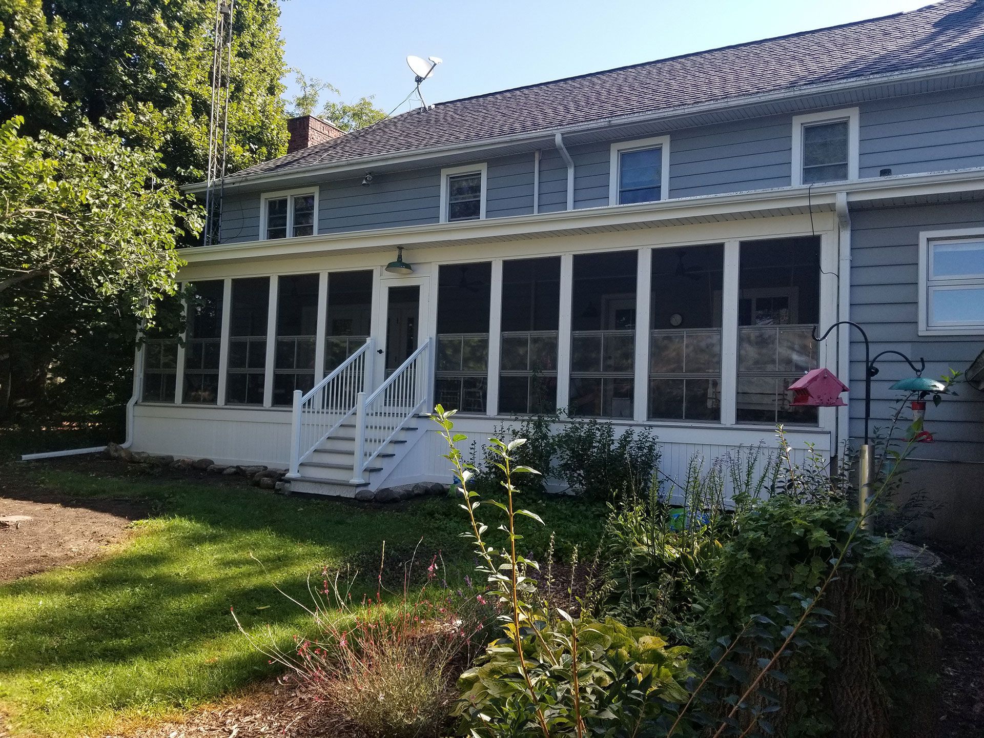 A large house with a screened in porch and stairs.