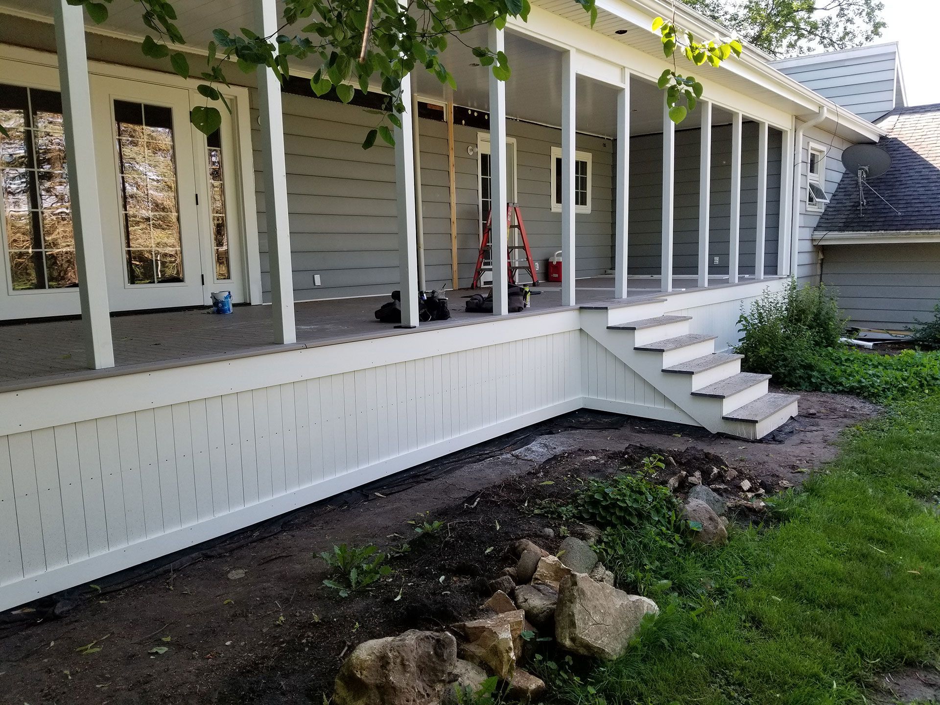 A white house with a porch and stairs.