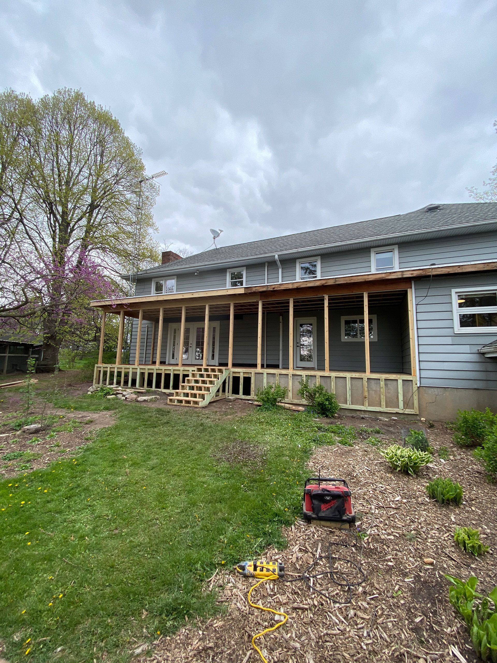 A house with a porch being built in the backyard.