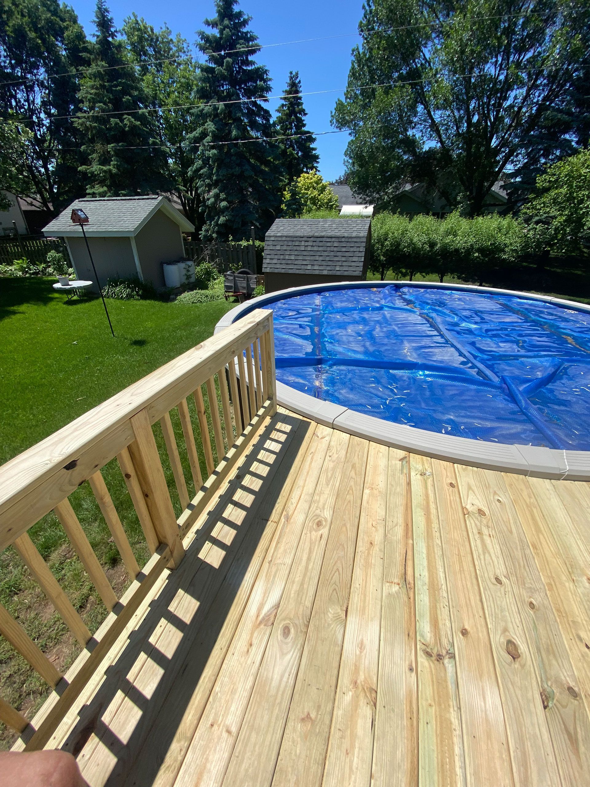 A wooden deck overlooking a swimming pool.