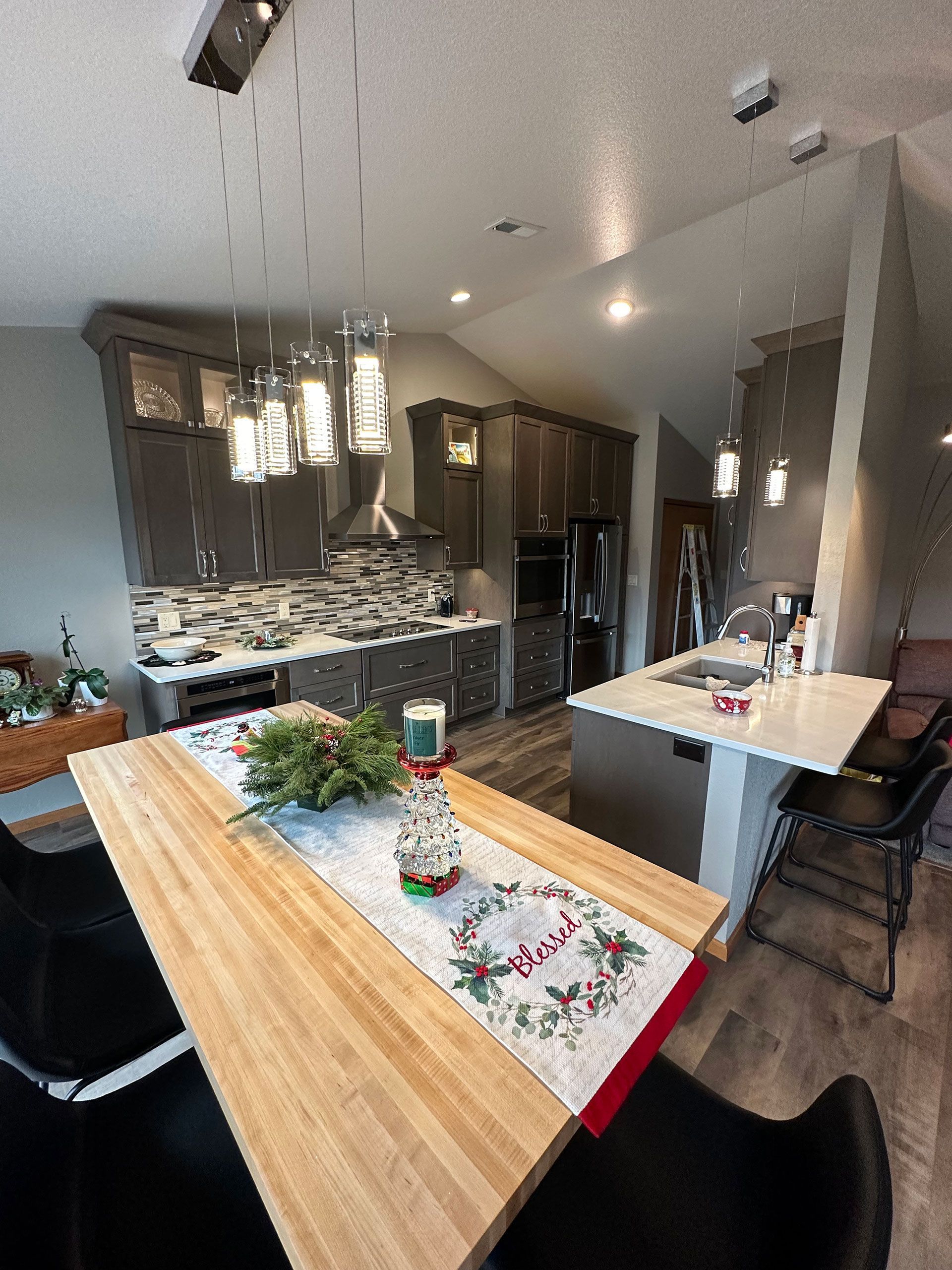 A kitchen with a wooden table and chairs and a Christmas table runner.