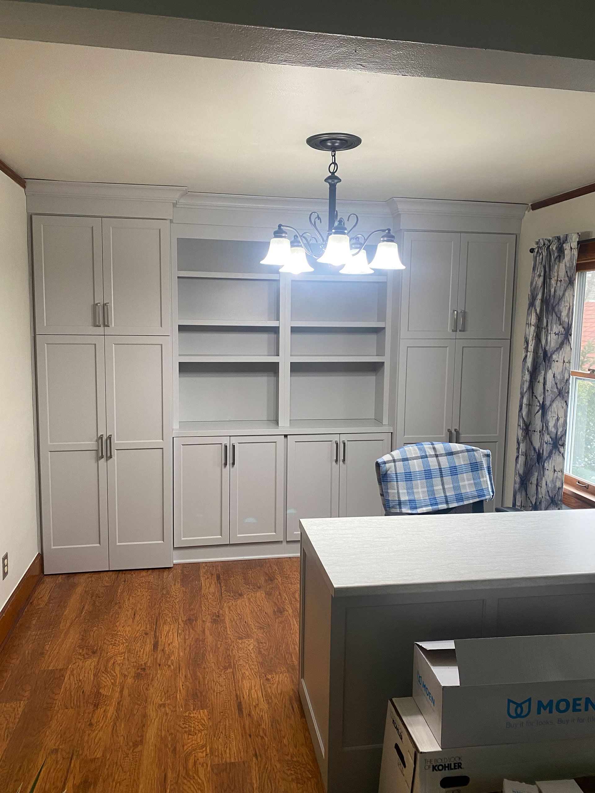 A room with a lot of cabinets and a chandelier hanging from the ceiling.