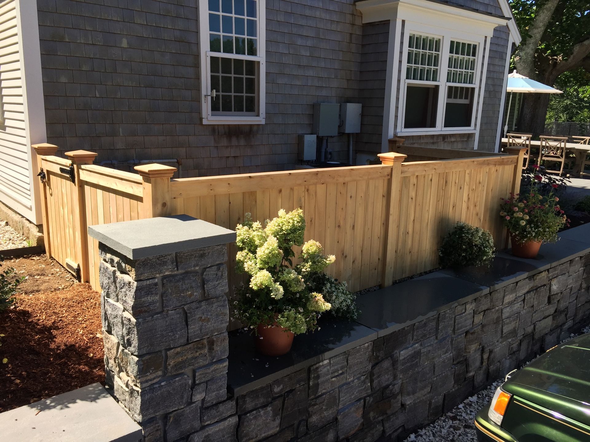 A wooden fence surrounds a brick wall in front of a house.