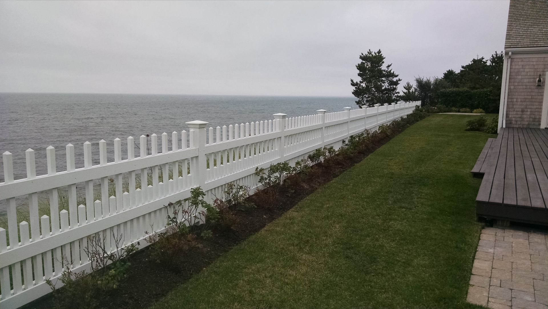 A white picket fence with a view of the ocean.