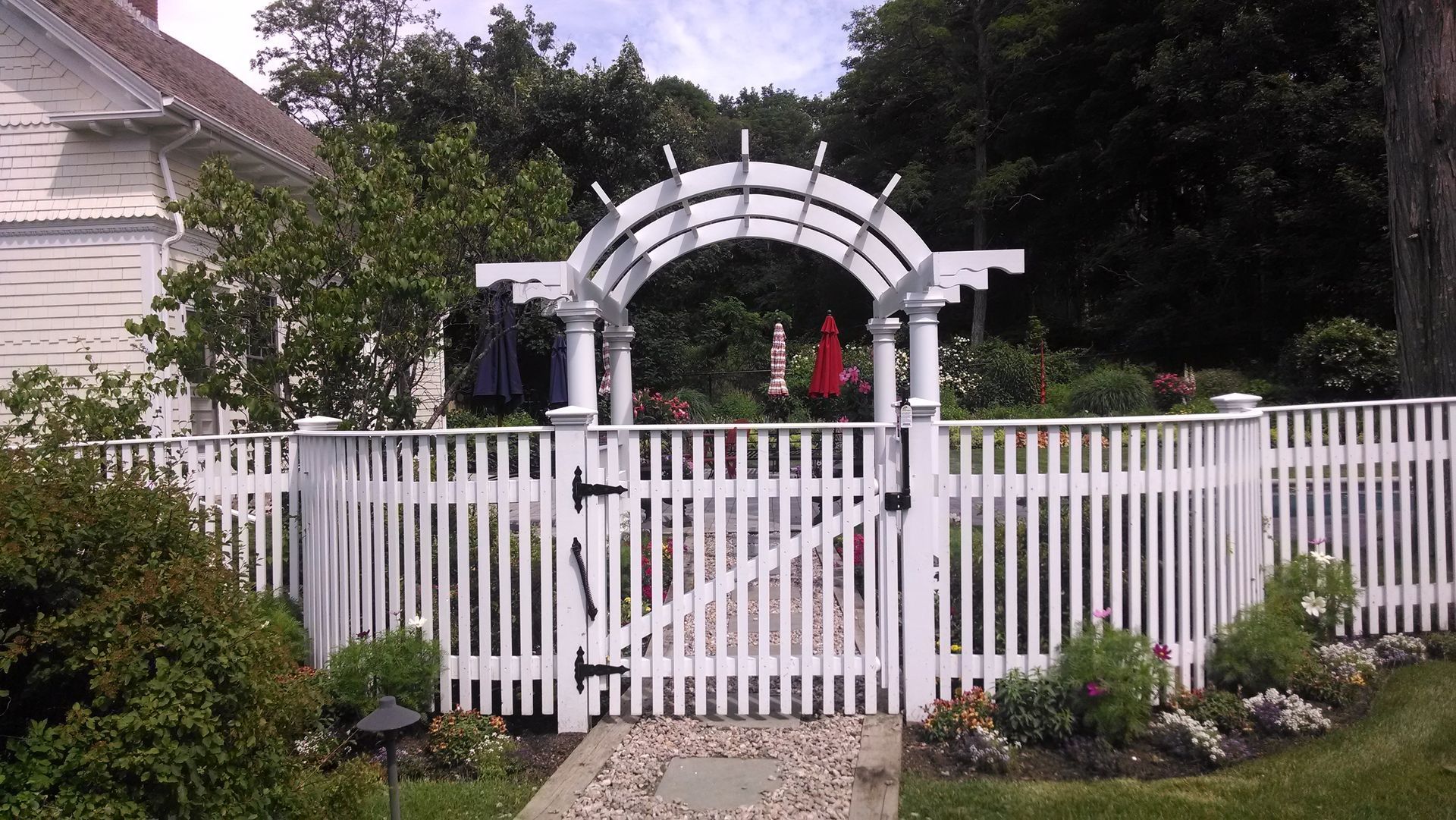 A white fence with a gate in front of a house.