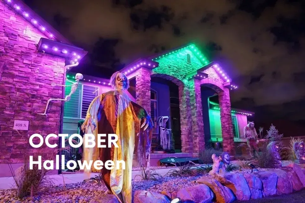 A house decorated for Halloween with purple and green lights, and spooky figures.