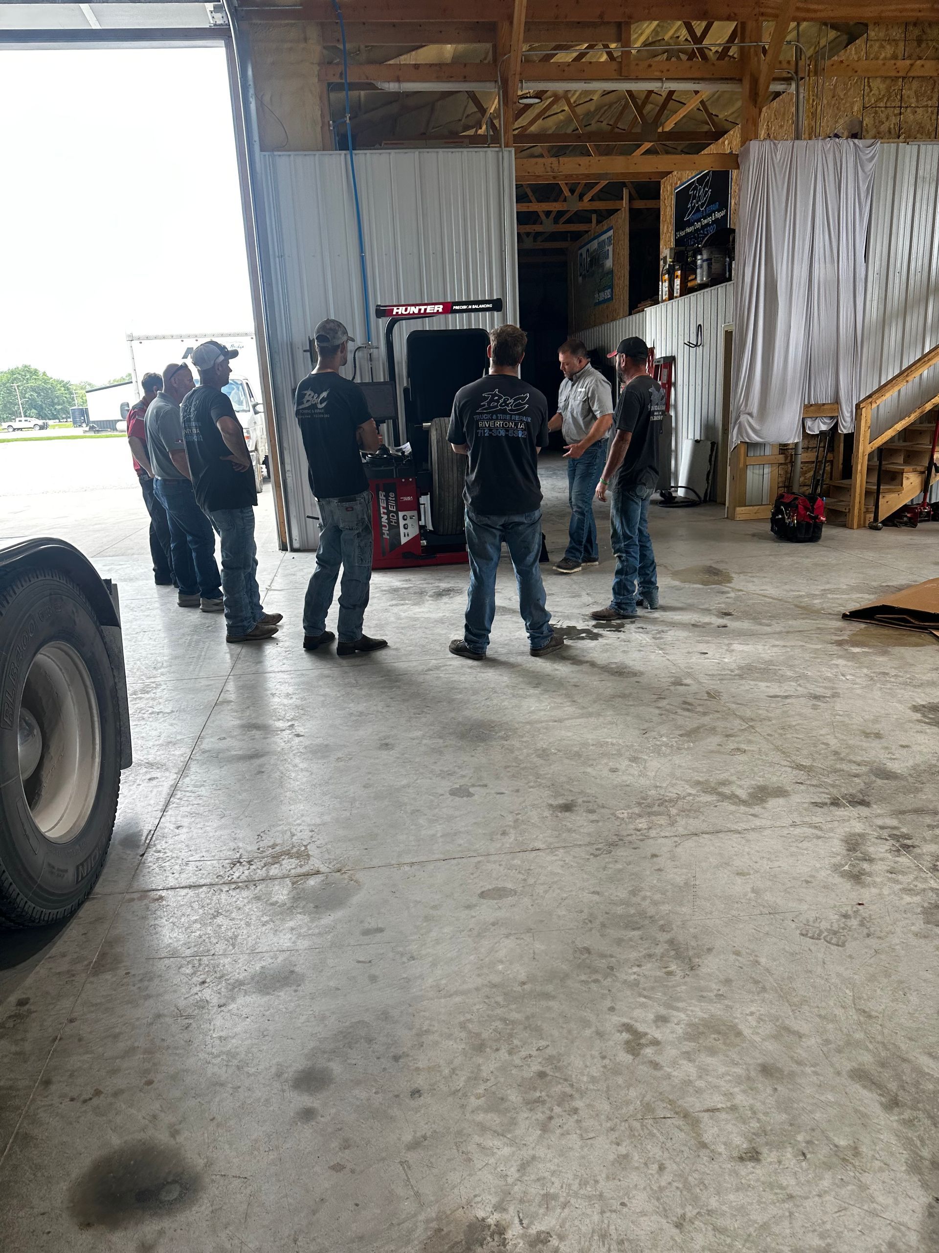 Workers standing in a warehouse beside a large truck and open loading bay.