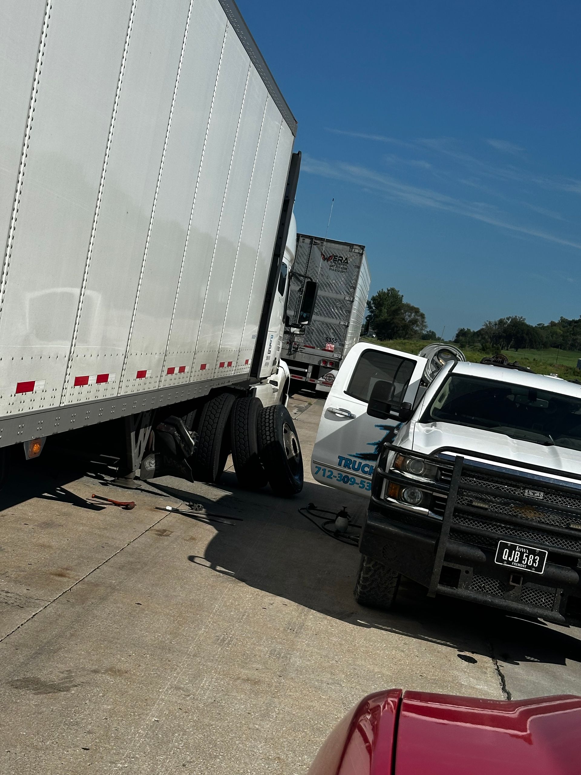 Multi-vehicle crash on a highway shoulder with a white semi-truck, white SUV, and black police vehicle