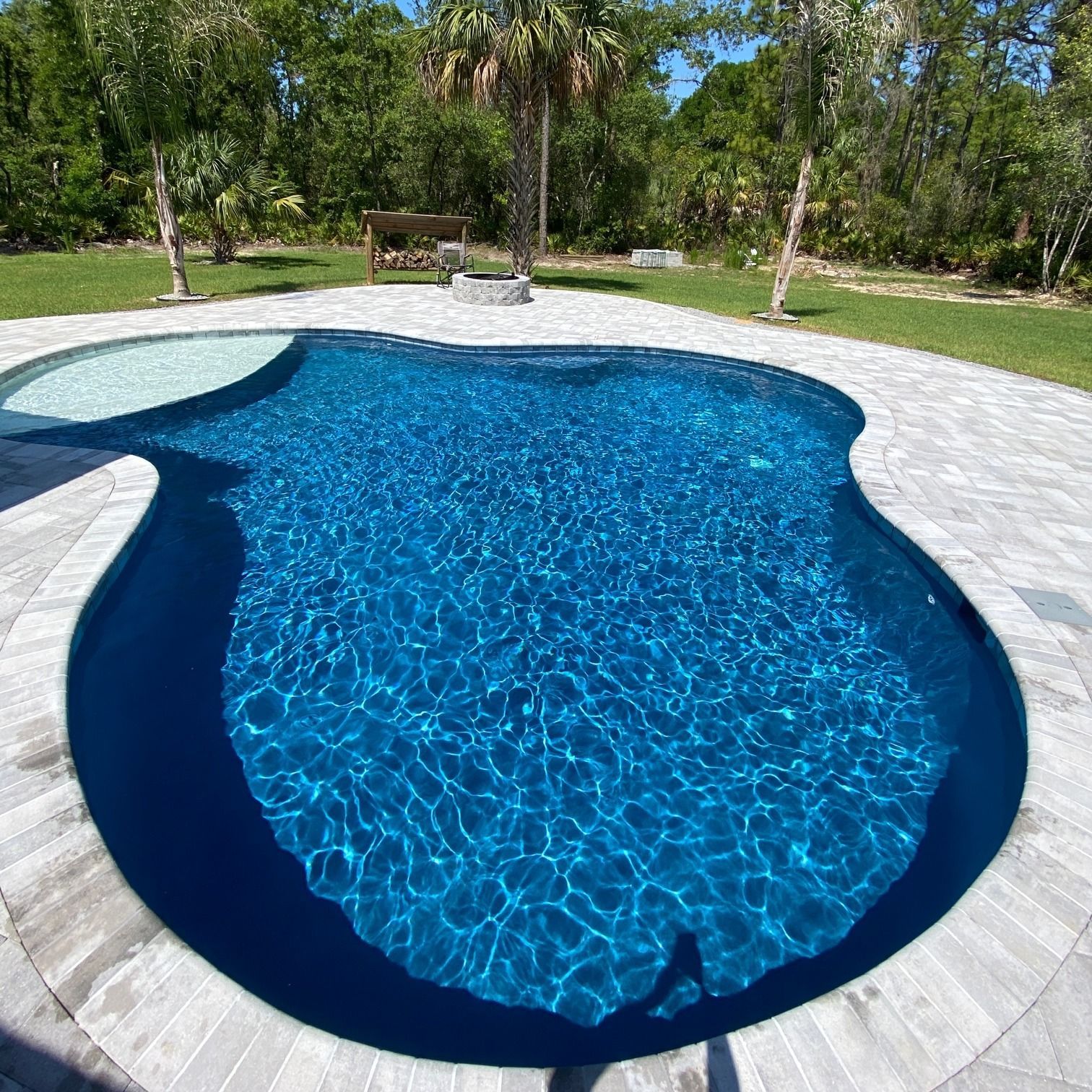 A large swimming pool surrounded by trees and grass
