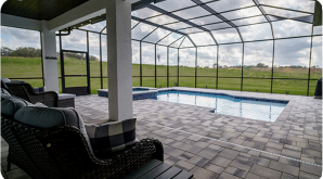 A screened in patio with a swimming pool and chairs.