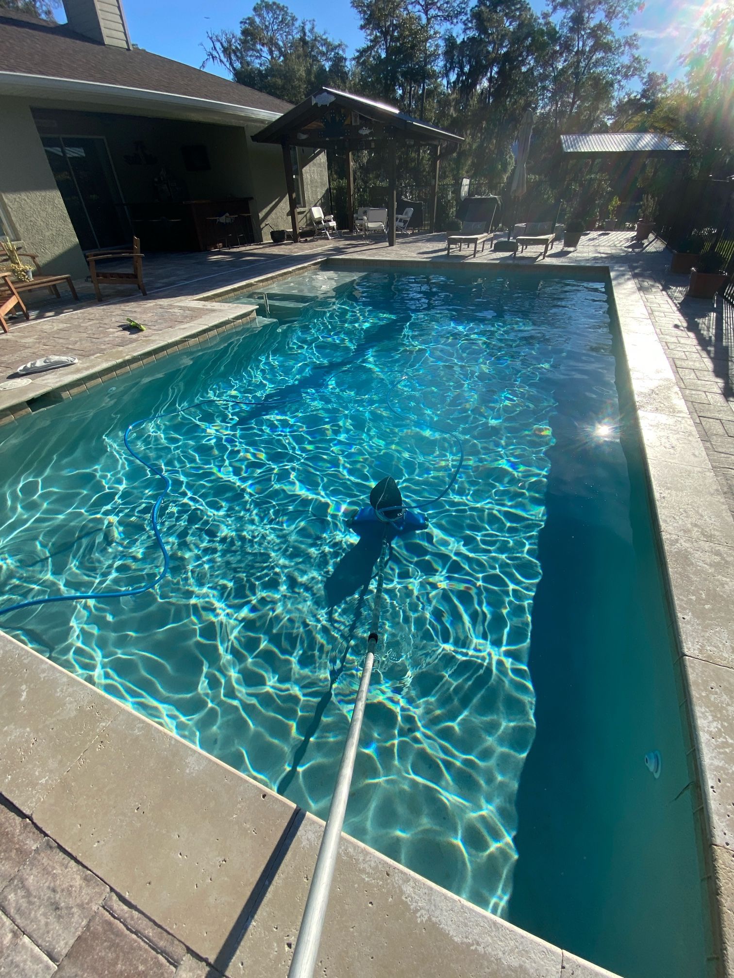 A large swimming pool is being cleaned by a person with a hose.