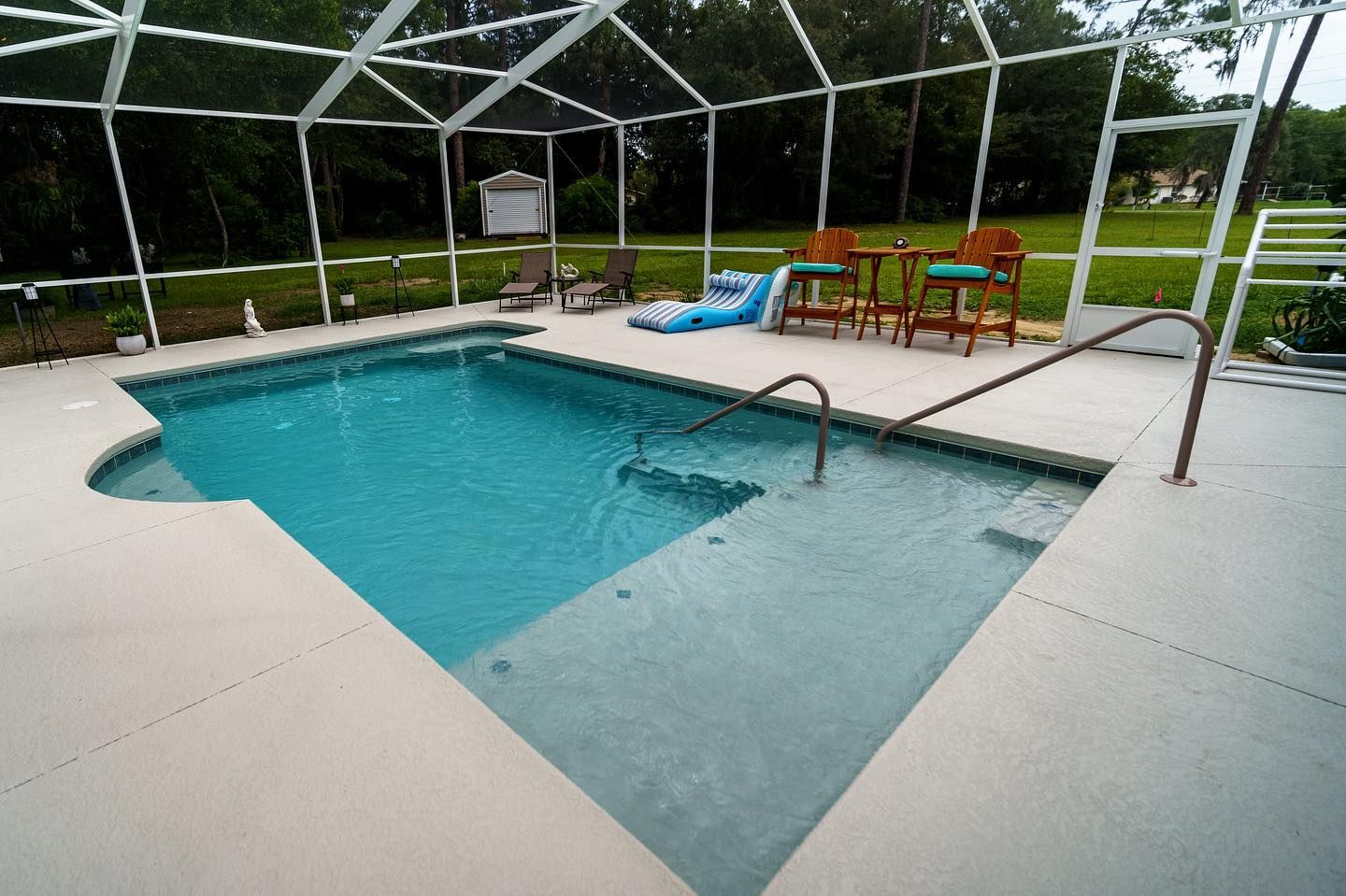 A large swimming pool is surrounded by a screened in area.
