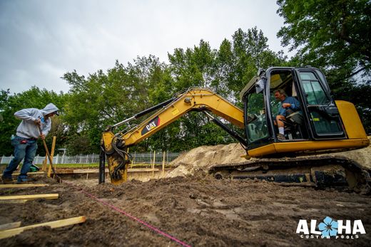 A man is driving a yellow excavator in a dirt field.