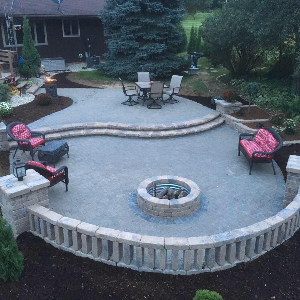 Patio with fire pit, seating, and dining area surrounded by a stone retaining wall.