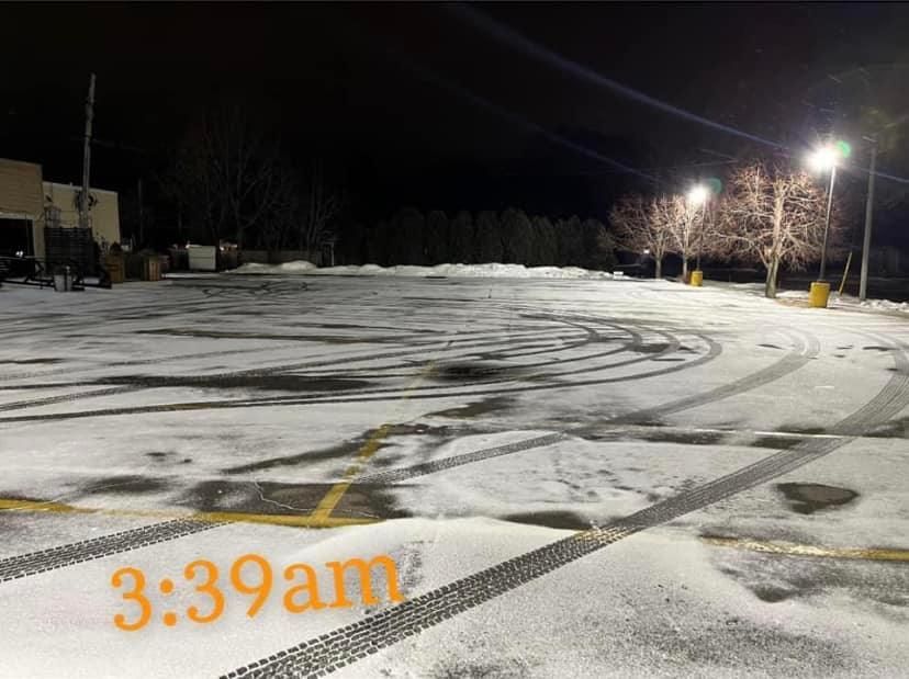 Snow-covered parking lot at night with tire tracks, illuminated by street lights, time stamp: 3:39 am.