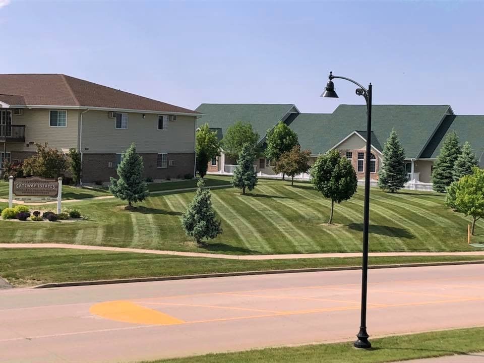 Street view of apartments with freshly mowed lawn, a lamppost in foreground.
