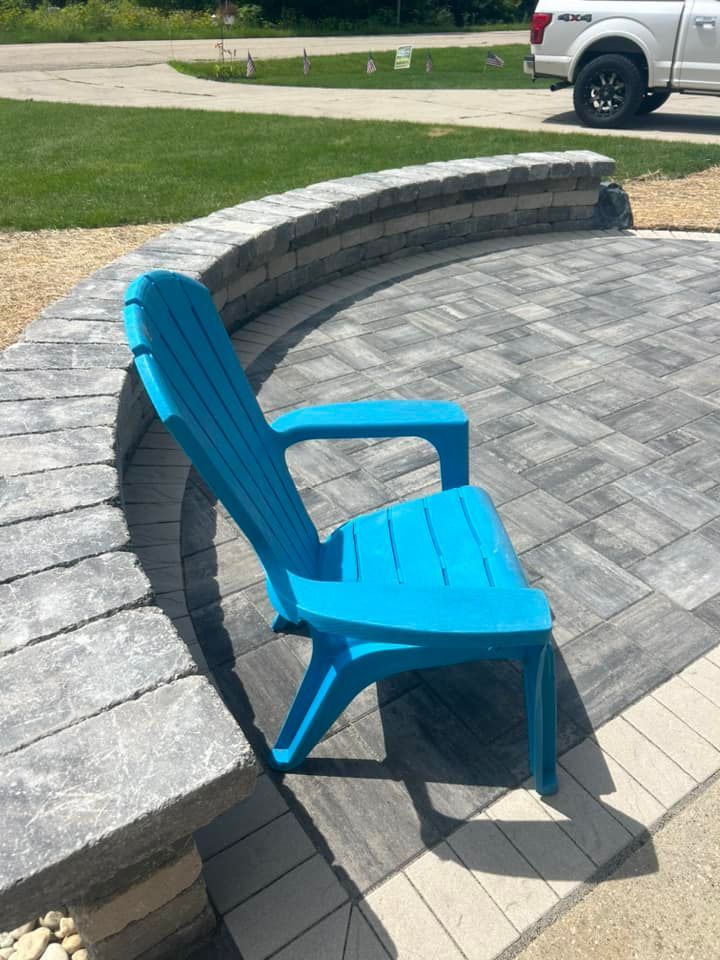 Blue plastic chair on brick patio beside a curved retaining wall.