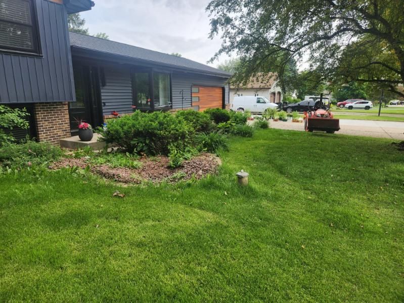 House exterior with landscaping and lawn; a person mowing grass, neighborhood in the background.