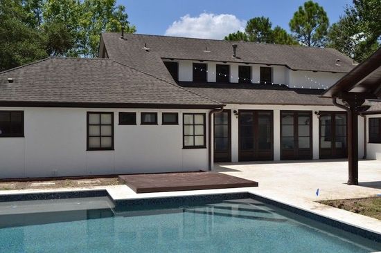 A large white house with a swimming pool in front of it.