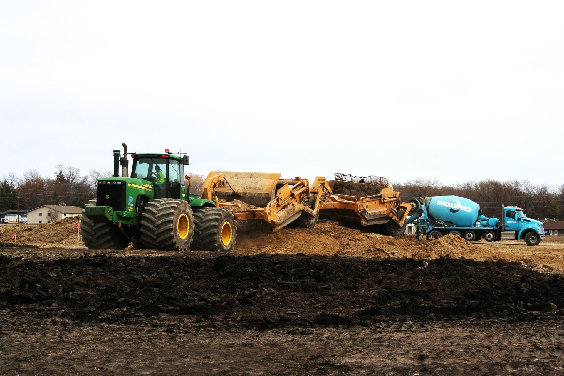 A green john deere tractor is driving through a dirt field