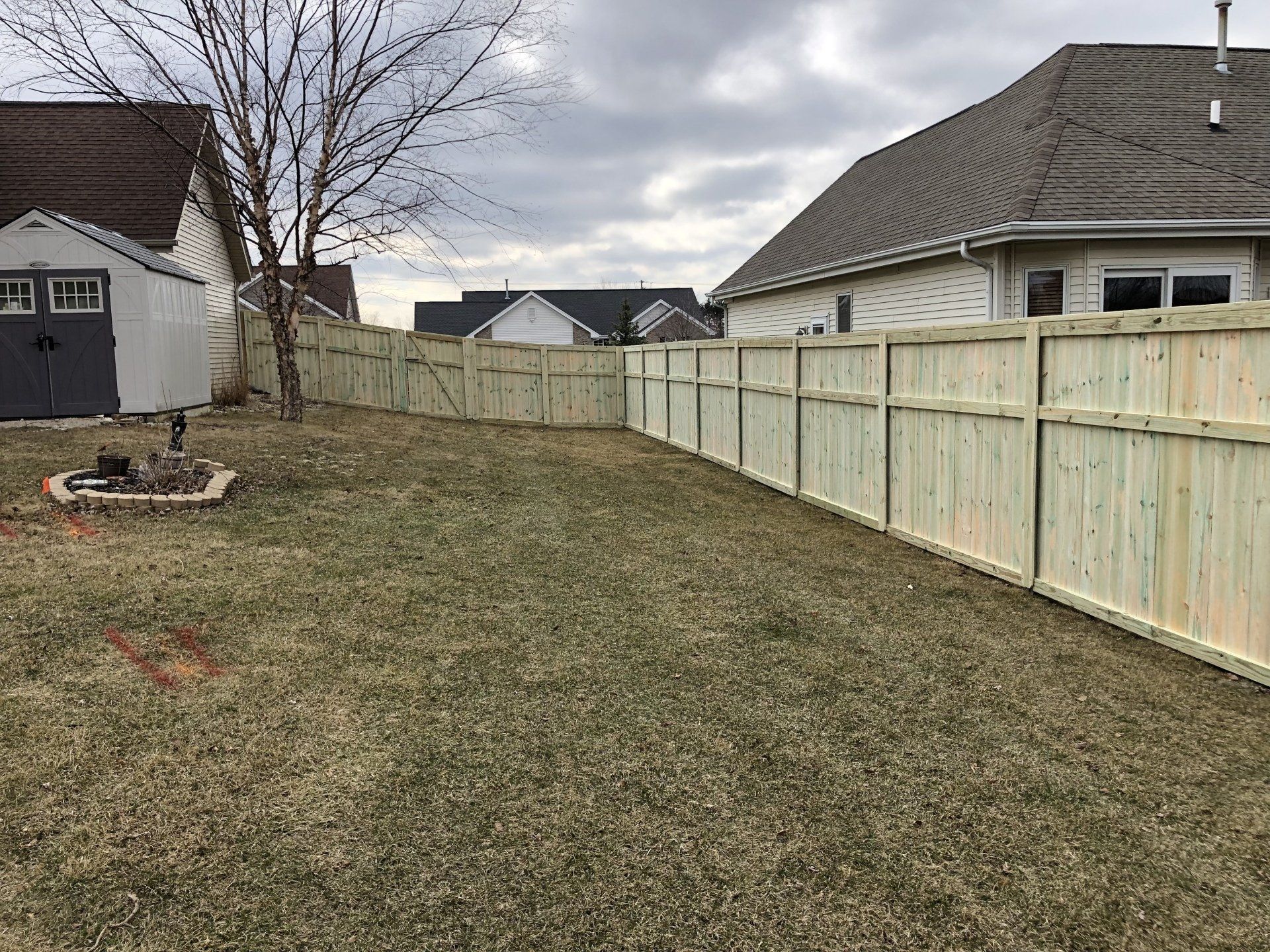 There is a wooden fence in the backyard of a house.