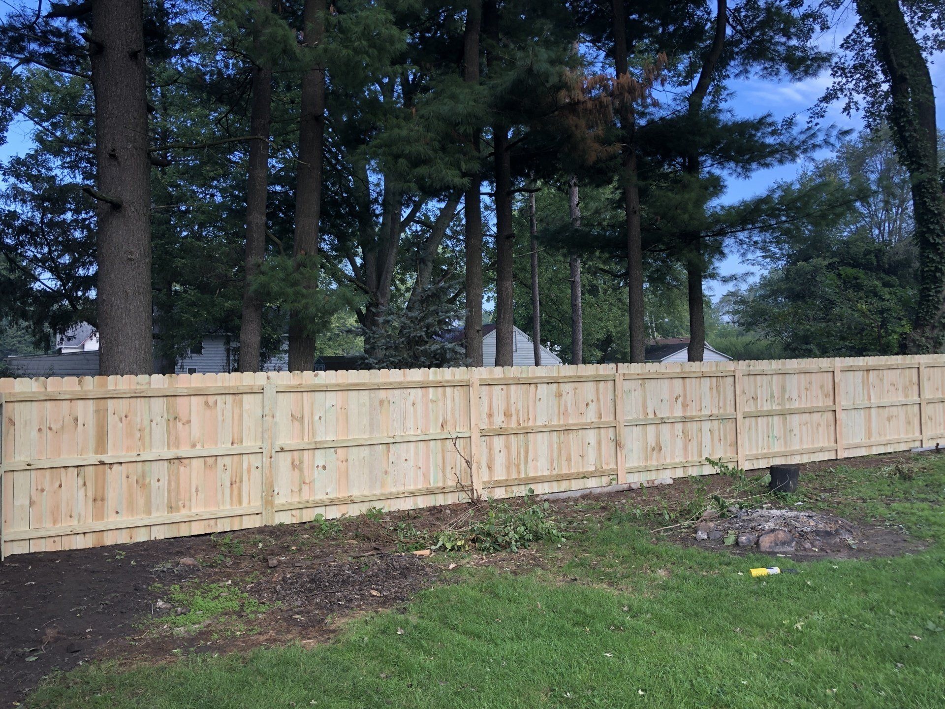 A wooden fence is surrounded by trees in a backyard.