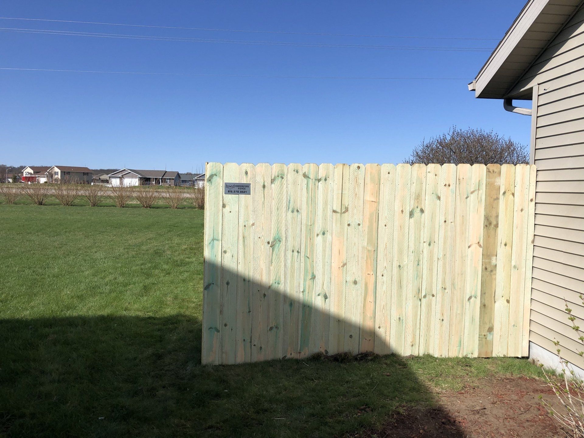 A wooden fence is in the backyard of a house.