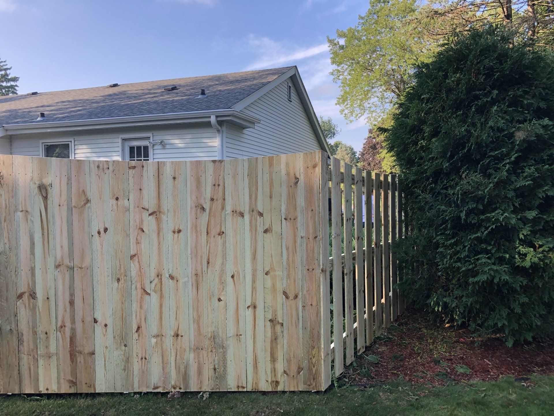 A wooden fence is in front of a house.