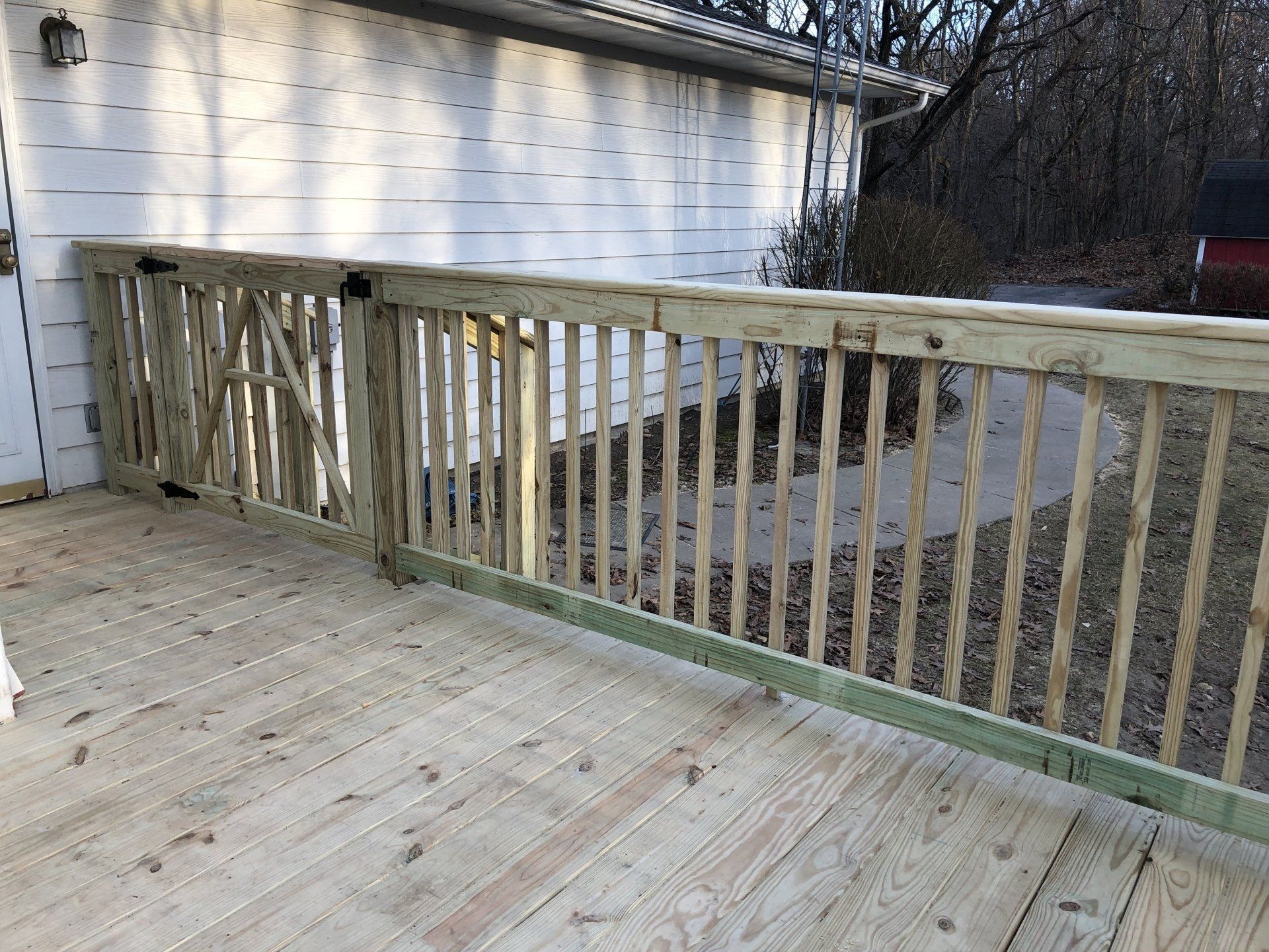 A wooden deck with a railing in front of a white house.
