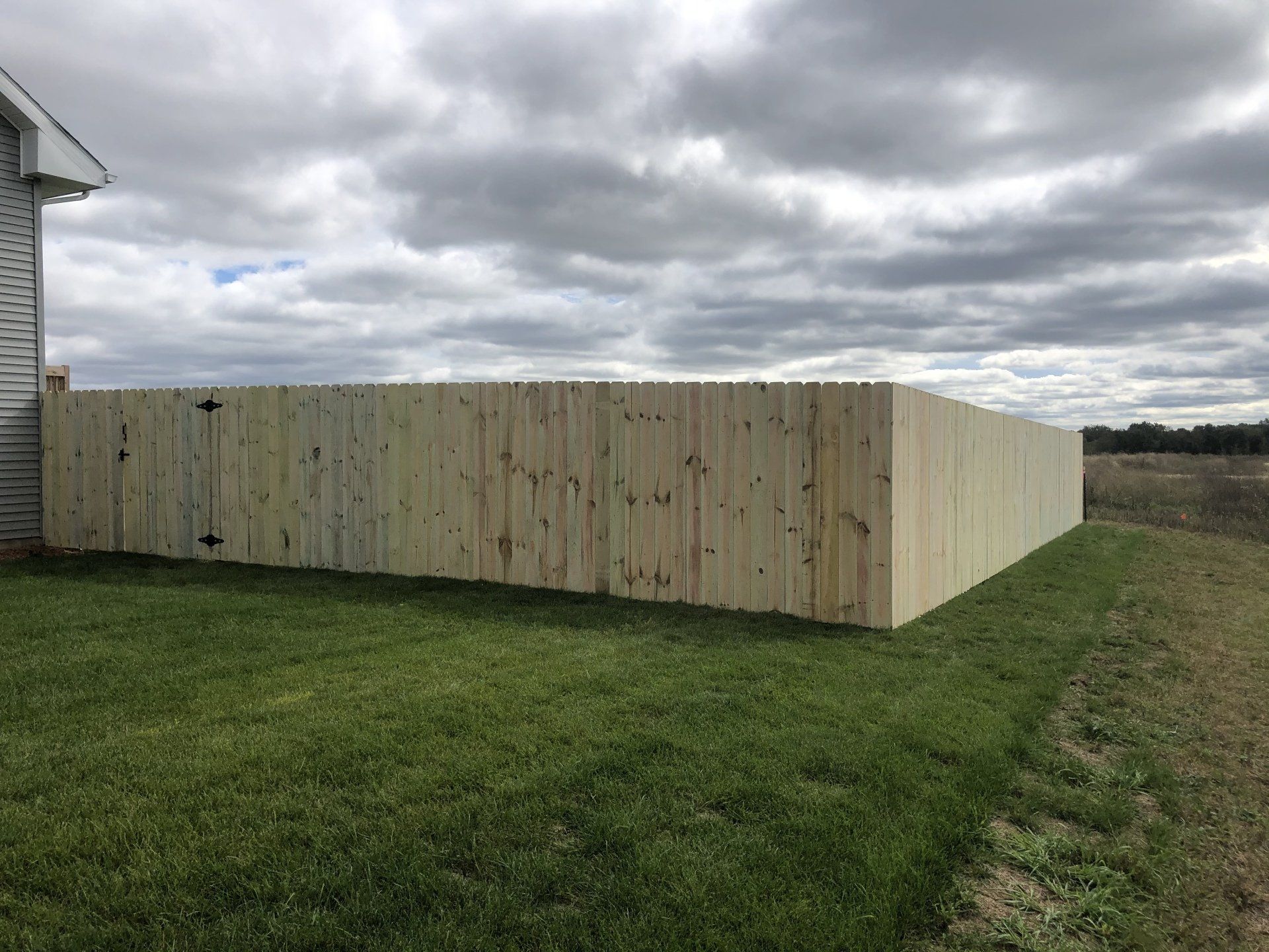 A wooden fence is sitting in the middle of a lush green field.