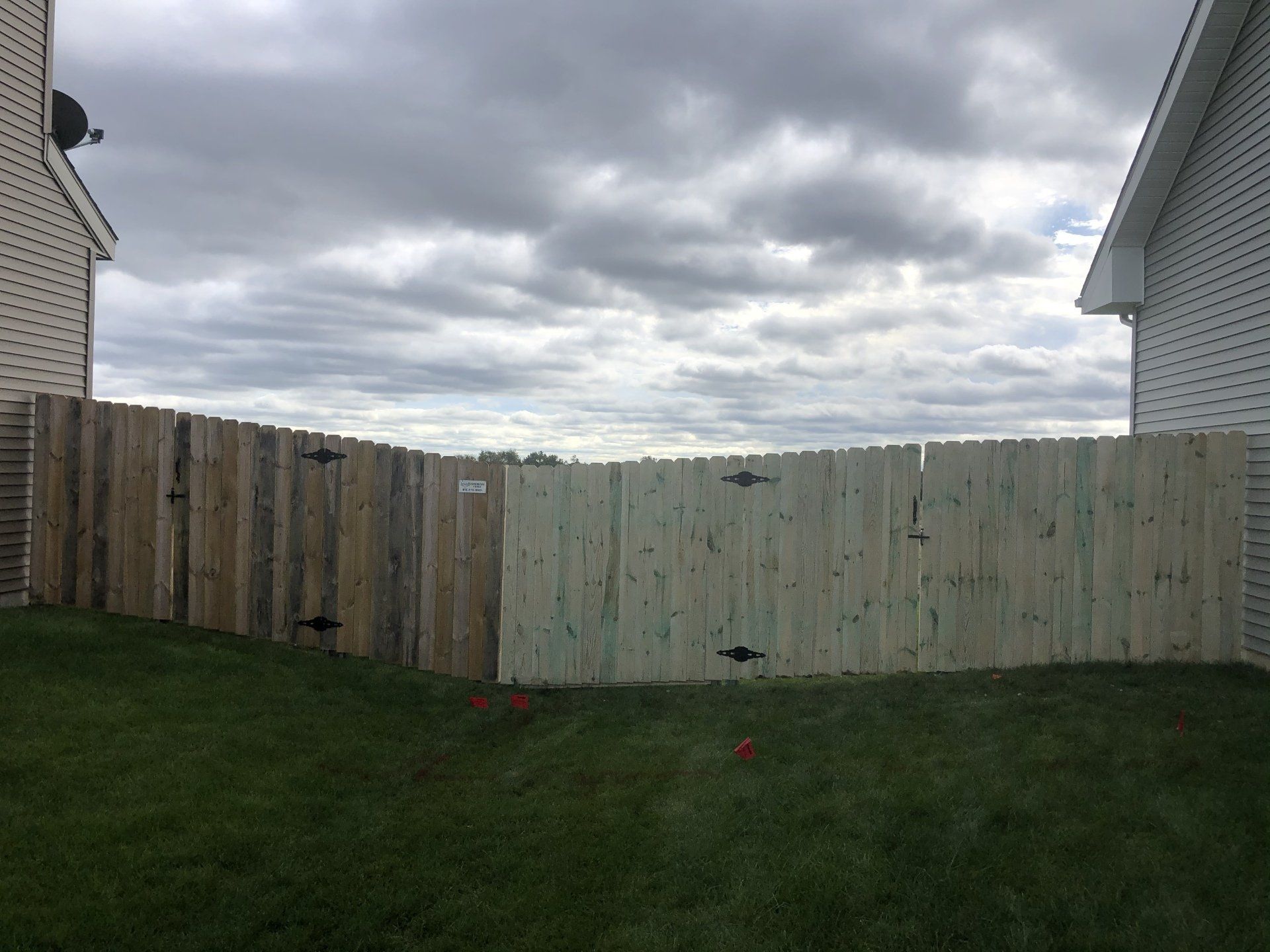 A wooden fence is in the backyard of a house.