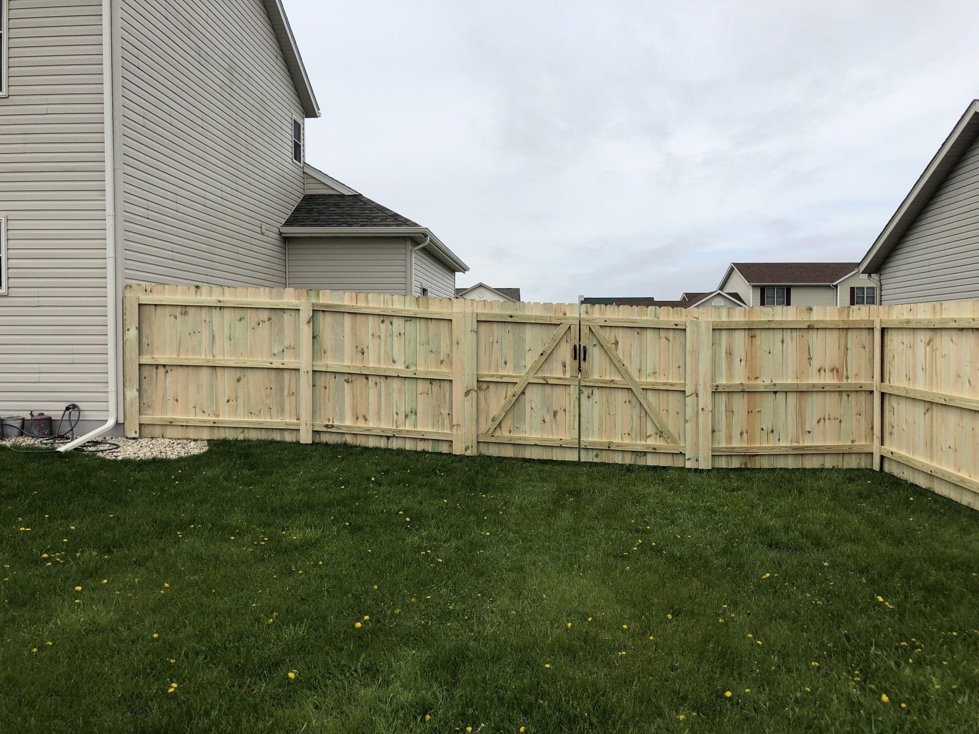 A wooden fence with a gate in the backyard of a house.