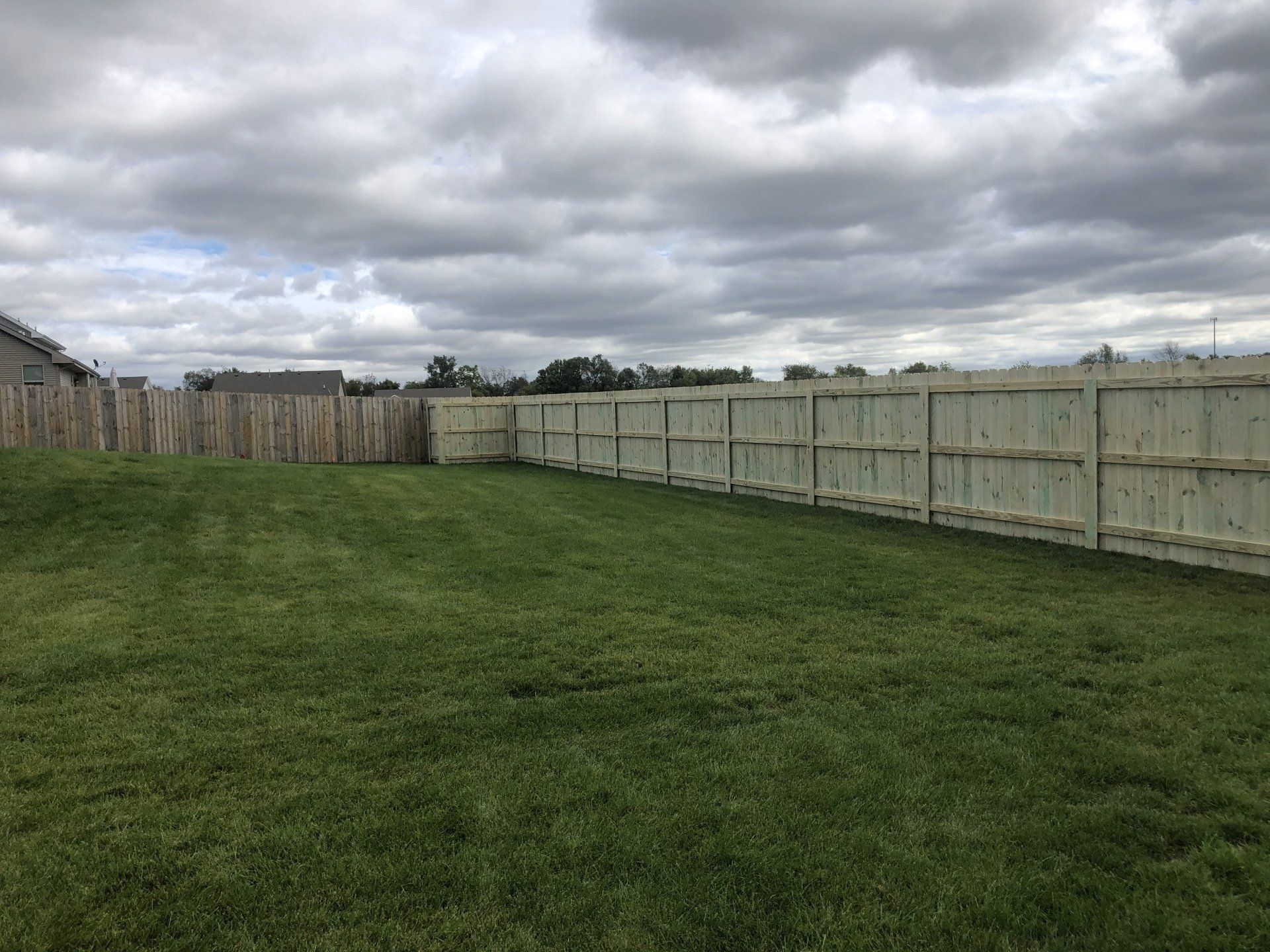 A wooden fence surrounds a lush green field.