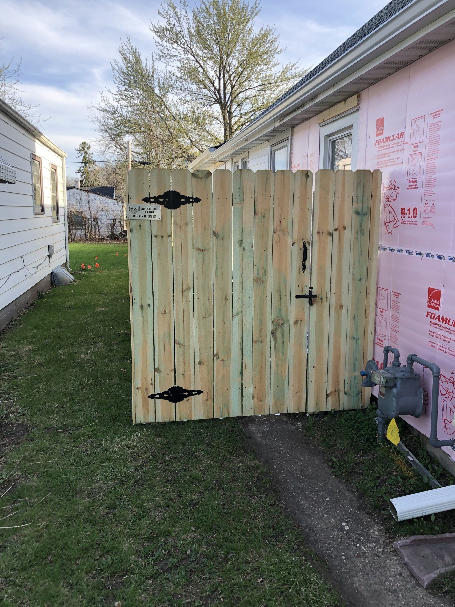 A wooden fence is sitting in the grass next to a house.