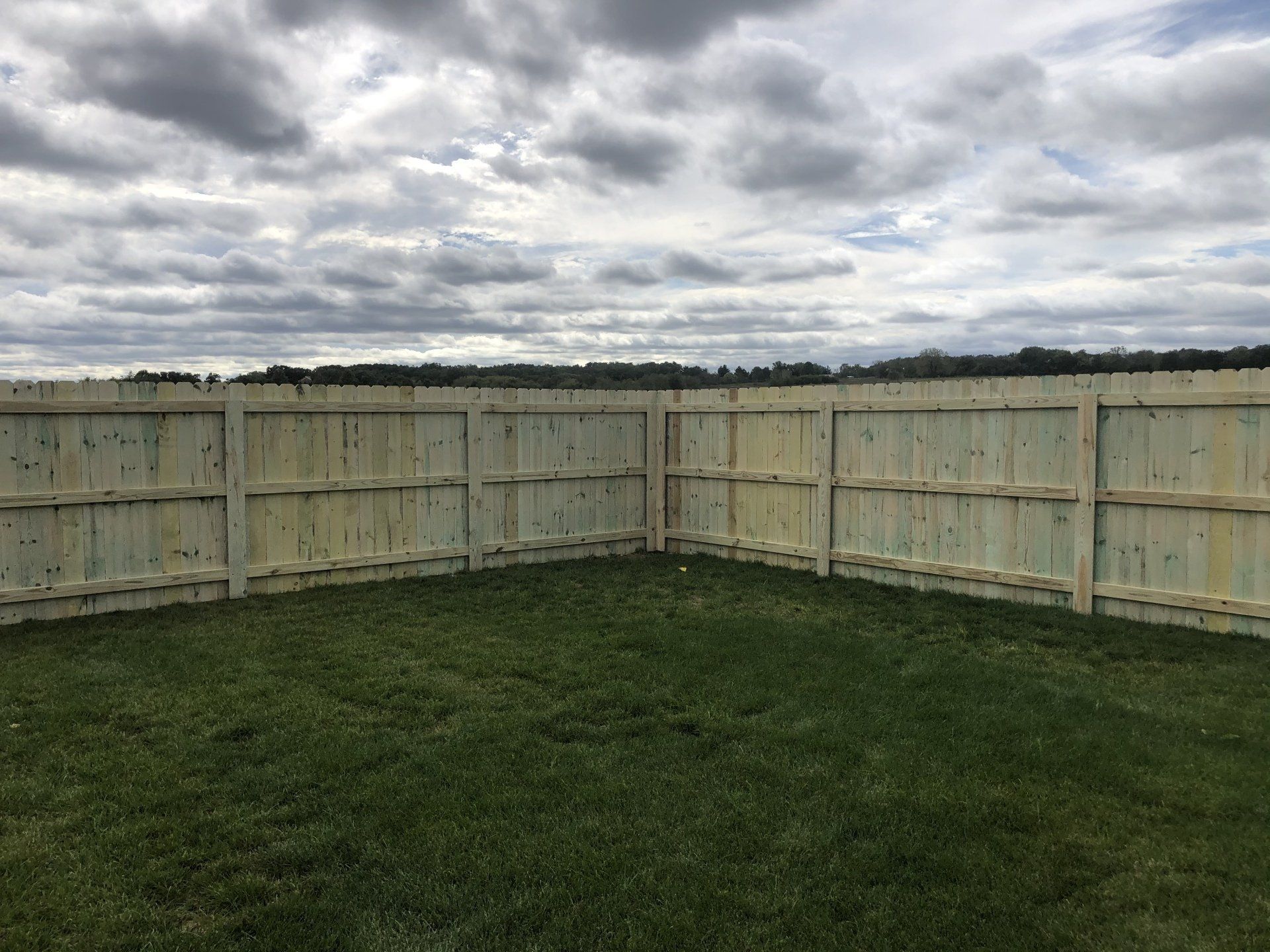 A wooden fence is in the middle of a lush green field.