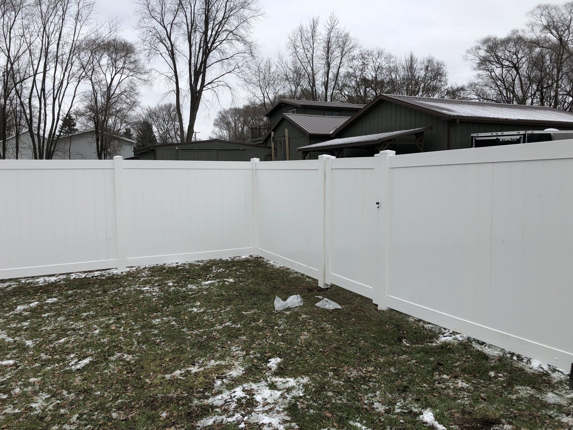 A white fence is in the backyard of a house.