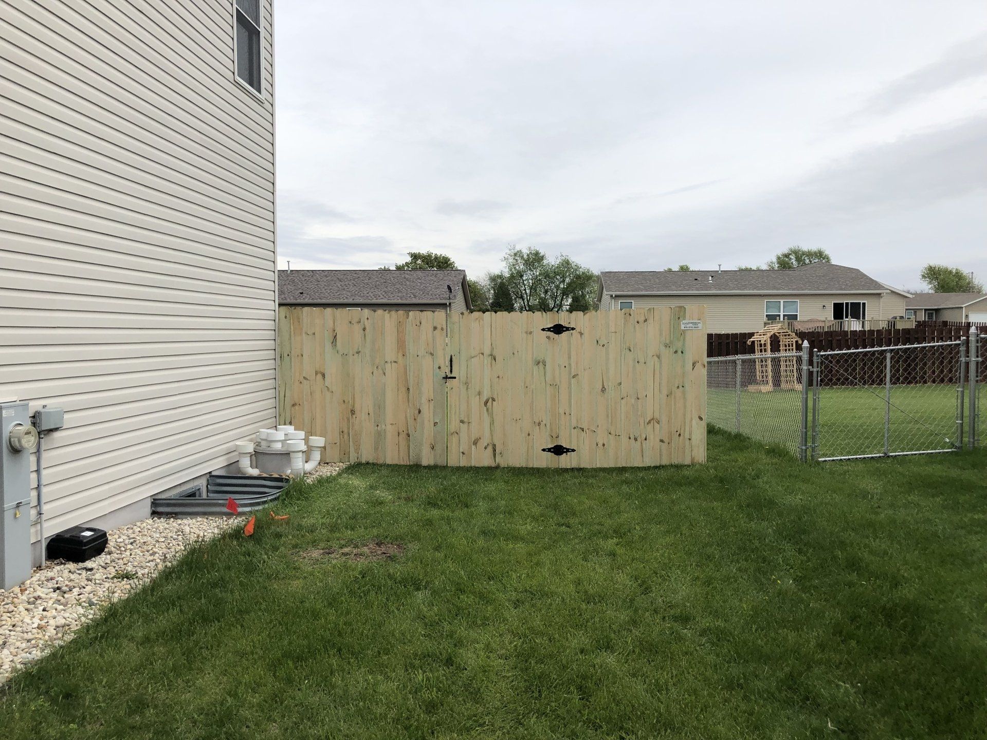 A wooden fence is in the backyard of a house.