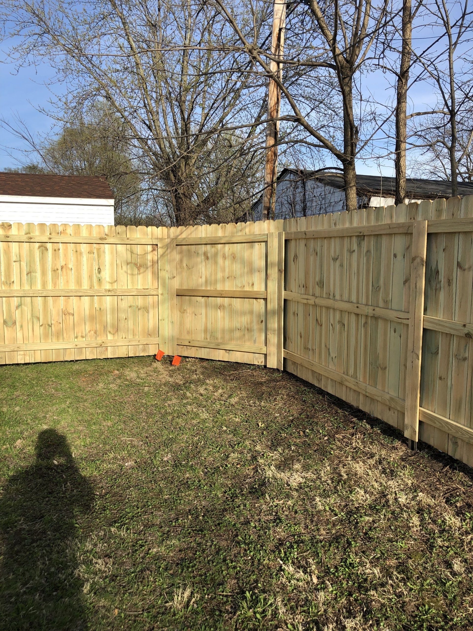 A wooden fence is in the backyard of a house.