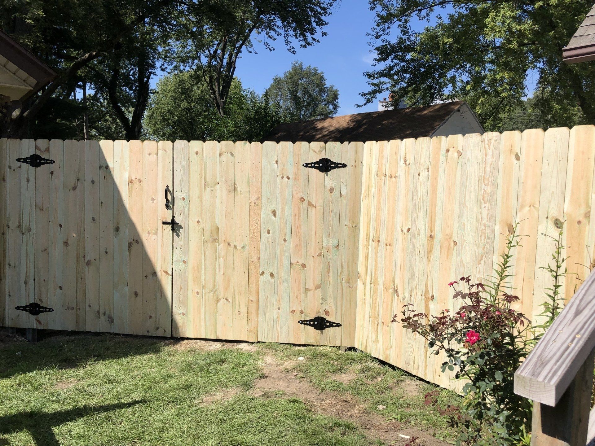 A wooden fence with a gate in the backyard of a house.