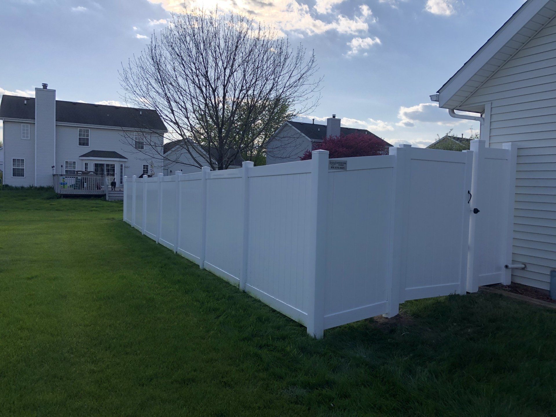 A white fence is in the backyard of a house.