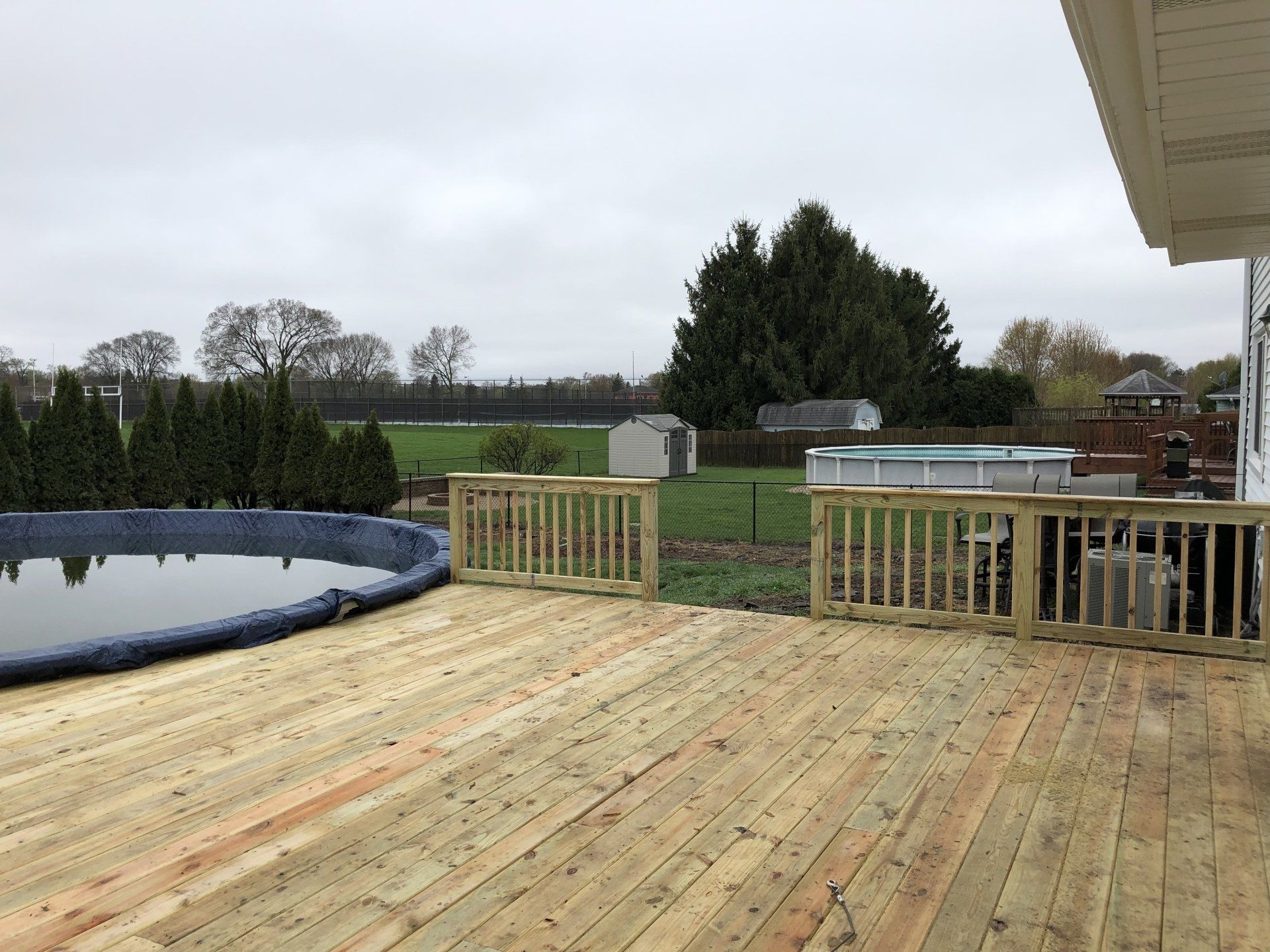 A wooden deck with a pool in the background.