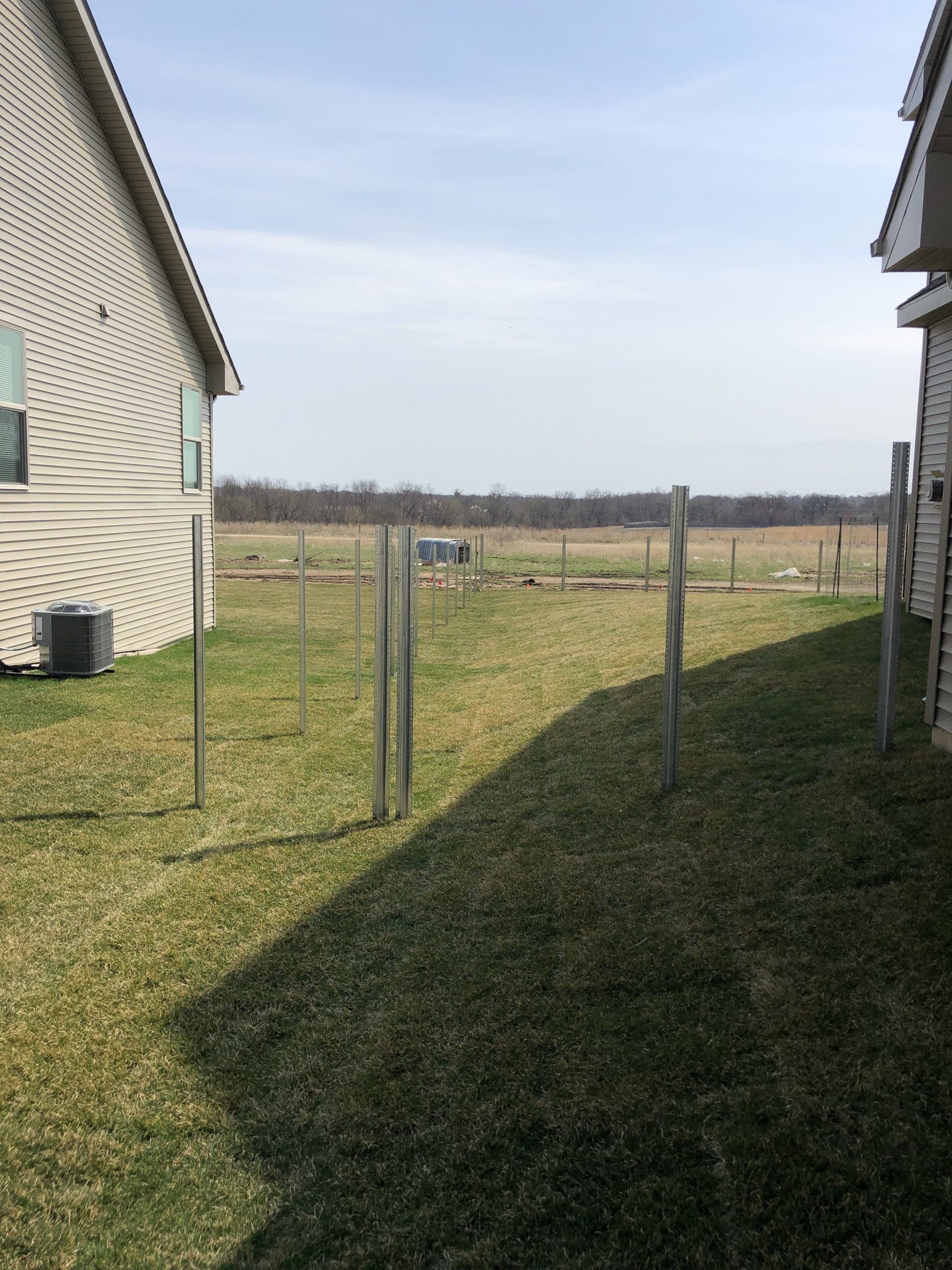 A backyard with a fence and a house in the background