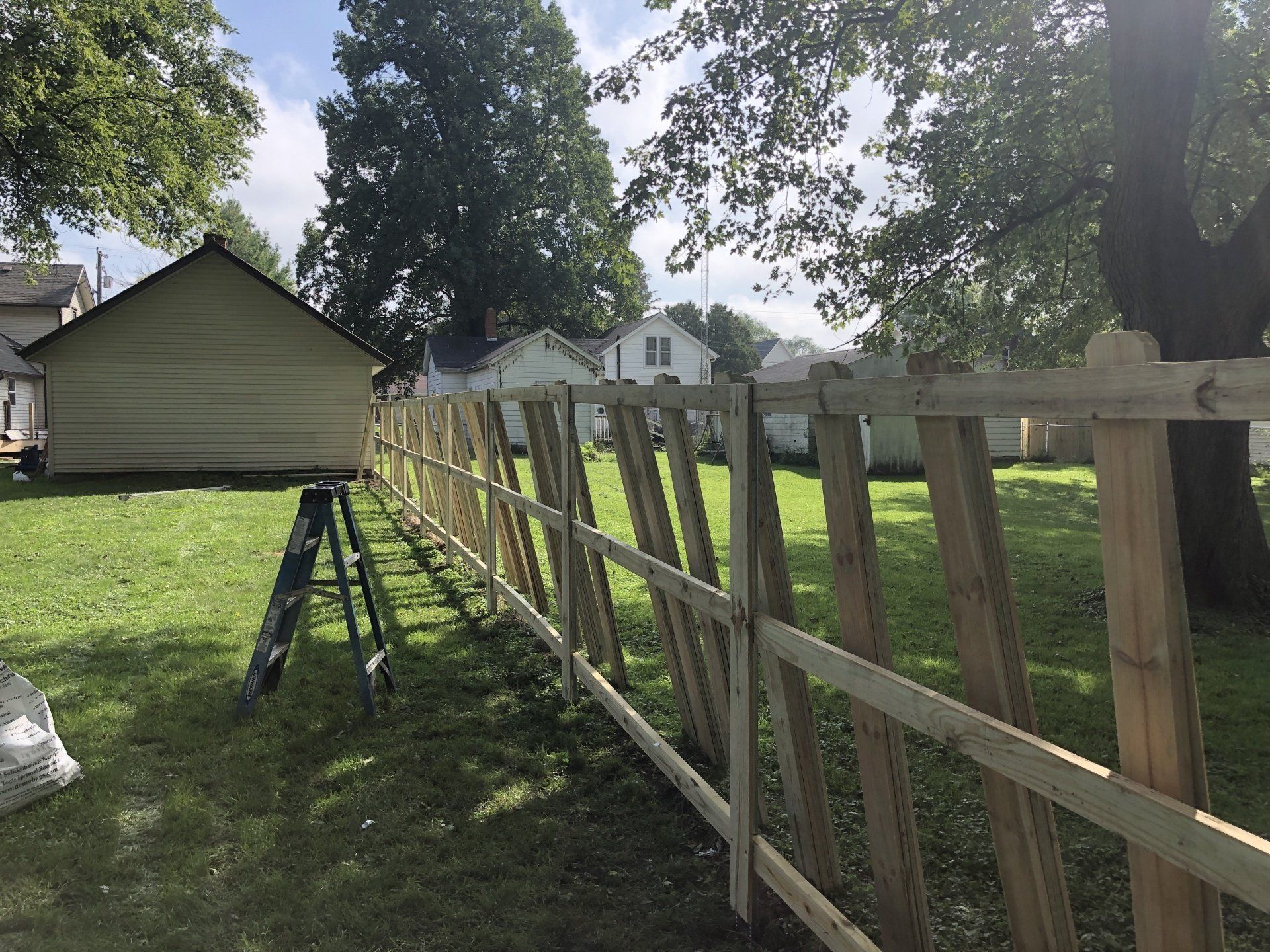 A wooden fence is being built in the backyard of a house.