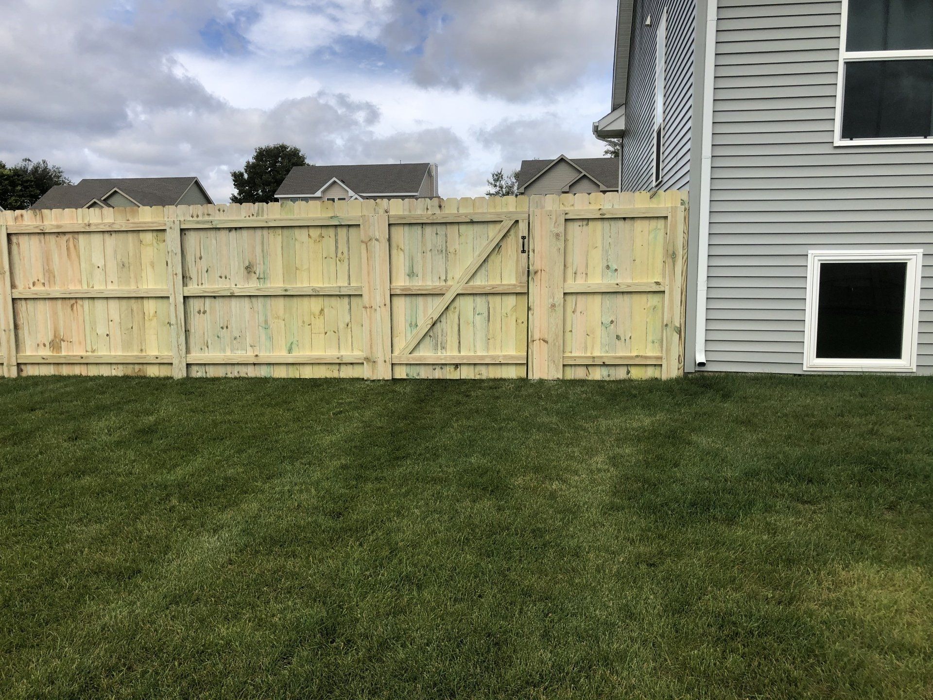 A wooden fence is in the backyard of a house.